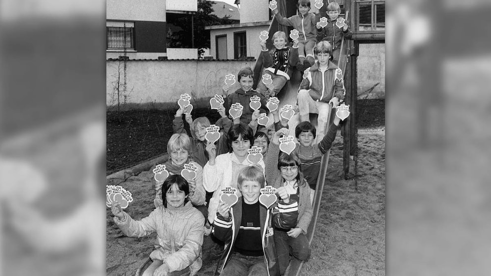 Spielplatz Koblenz – „Ein Herz für Kinder"-Aufkleber in den Händen von den Kindern auf der Rutsche @Manusco